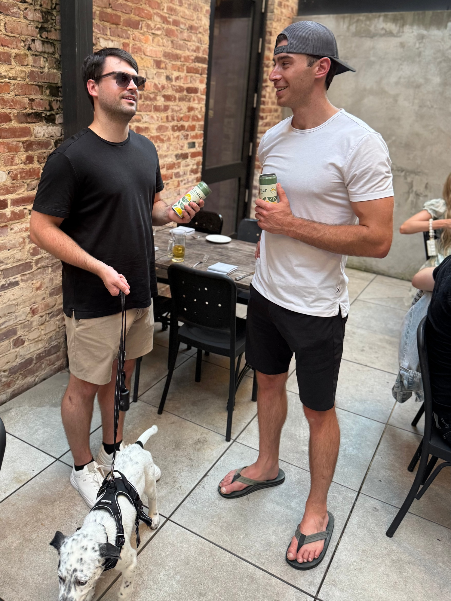 Two men standing outdoors with a dog, holding Coaster by Lift&Coast and smiling.